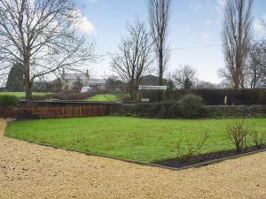 a yard with a fence and a green field at Brookside Cottage in Forton
