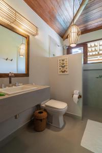 a bathroom with a sink and a toilet and a mirror at Pousada Recanto do Sol in Trancoso