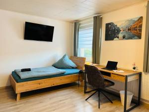 a room with a bed and a desk with a laptop at Gästehaus Trockau in Pegnitz