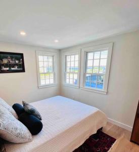 a bedroom with a large bed with two windows at Historic 2 Bedroom with marble baths and water views in Newburyport
