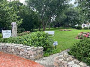 a garden with a stone wall and signs in a yard at Historic 2 Bedroom with marble baths and water views in Newburyport