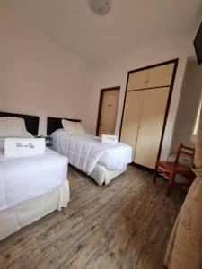 a hotel room with two beds and a mirror at Hotel Perla del Plata in Colonia del Sacramento