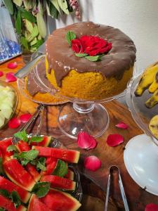 a chocolate cake on a table with a plate of fruit at FAZENDAS ANTIGAS HOTEL in Sumidouro