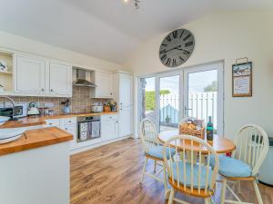 a kitchen with a table and chairs and a clock on the wall at Puffin Cottage in Peel