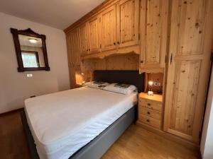 a bedroom with a large bed and wooden cabinets at 060 Bilocale, Giustino in Giustino