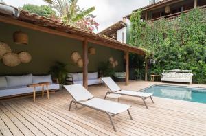 a wooden deck with white chairs and a swimming pool at Pousada Recanto do Sol in Trancoso
