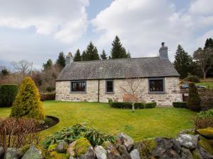 a stone house with a lawn in front of it at Craigellachie Cottage in Croy