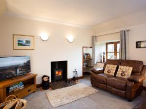 a living room with a couch and a fireplace at Craigellachie Cottage in Croy