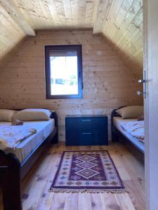 two beds in a room with a window and a rug at Brvnara “Vidik Breg” in Bajina Bašta