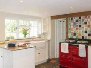 una cucina con armadi bianchi e un forno a piano cottura rosso di The Bothy a Lymington