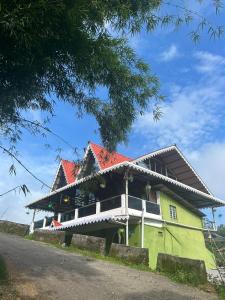 a green house with a red roof on a road at Mirik Homestay in Mirik