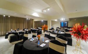 un salón de banquetes con mesas negras, sillas y flores en Hotel Montrose Kasauli !! Balcony Rooms !! Terrace !! Restaurant !! Spa, en Kasauli