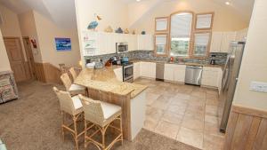 a kitchen with white cabinets and a island with chairs at Oceanfront, Wild Horses, Ocean Views, Private Pool, 4x2251, Beauty & The Beach in Knotts Island