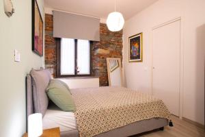 ein Schlafzimmer mit einem Bett und einer Ziegelwand in der Unterkunft Baby Art Apartment in Arona