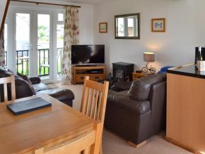 a living room with a leather couch and a television at Nightingale in Wroxham