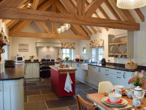 a large kitchen with wooden ceilings and a table at Soar Cottage in Dihewid
