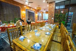 a restaurant with wooden tables and people standing in a room at MY HOME in Hue