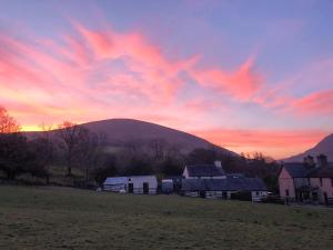 a sunset over a farm with a mountain in the background at Hendy in Waenfawr