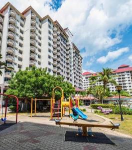 un parque infantil frente a un gran edificio en Cuti Cuti apartment Glory Beach en Port Dickson