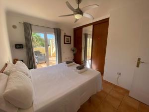a bedroom with a white bed with a ceiling fan at 60 El Sultan, 20 Pedroy Guy Vandaele in Corralejo