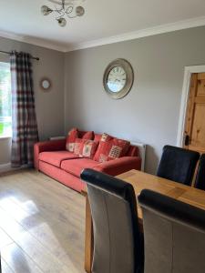 sala de estar con sofá rojo y mesa en Pat's Cottage, en Kinawley