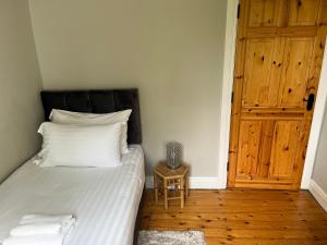 1 dormitorio con 1 cama con sábanas blancas y suelo de madera en Pat's Cottage, en Kinawley