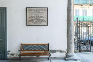 a wooden bench sitting next to a wall with a sign at La Dimora Della Torretta in Cantù