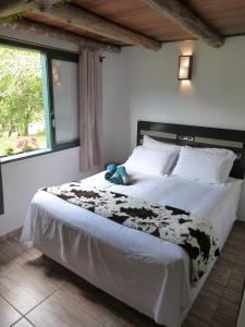 a bed with a black and white comforter and a window at Pouso das Águias in Nova Veneza