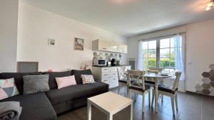 een woonkamer met een bank en een tafel en een keuken bij Ma cabane de plage in Saint-Valery-sur-Somme