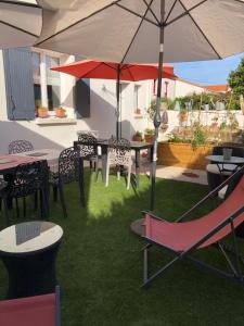 eine Terrasse mit Tischen, Stühlen und einem Sonnenschirm in der Unterkunft BnB Montacutain in Montaigu-Vendée