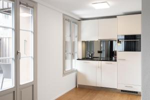 uma cozinha com armários brancos e uma janela em Studio ALBERT Interlaken em Interlaken