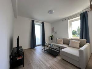 a living room with a couch and a tv at FeelHome-GolfClub-Balkon-4 Gäste-WiFi-Smart TV in Ebreichsdorf