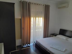 Schlafzimmer mit einem Bett und einem Fenster mit Vorhängen in der Unterkunft Hotel Unik in Pogradec