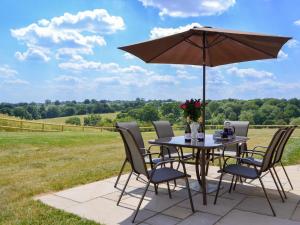 a table and chairs with an umbrella on a patio at Orchard Cottage in Morville