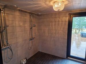ein Bad mit einer Dusche, einem Fenster und einem Kronleuchter in der Unterkunft Tuorilan tupa in Jämsä