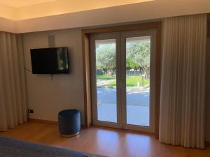 a bedroom with a sliding glass door with a television at Casa de Lamaçais in Vilela
