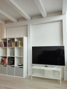 uma sala de estar branca com uma televisão e prateleiras de livros em LLHOME BOLOGNA Elegante monolocale ristrutturato con posto auto coperto em Bolonha