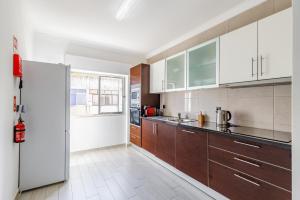 eine Küche mit Holzschränken und einem Kühlschrank in der Unterkunft Sleeptubal Moderne Accommodatie in Alhos Vedros