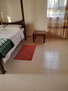 een slaapkamer met een bed en een tafel op een tegelvloer bij Topsta Apartment in Kisii