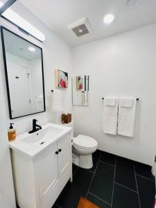 a white bathroom with a toilet and a sink at Brand New Luxury Fully Furnished Studio Suite in Oakland