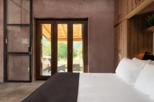 a bedroom with a white bed and a glass door at Hidden Stone Chalet in Zarouchla