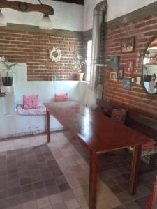 - une table en bois dans une chambre dotée d'un mur en briques dans l'établissement Hermosa casa a 200 m de la playa, à Balneario Mar Chiquita