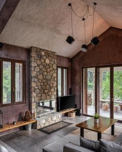 a living room with a tv and a stone wall at Hidden Stone Chalet in Zarouhla