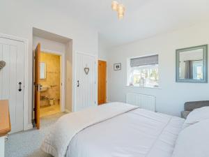 a white bedroom with a bed and a bathroom at Puffin Cottage in Peel