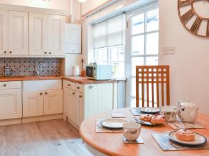 a kitchen with a wooden table with plates on it at Ukc4174 The Cottage By The Sea in Littlehampton