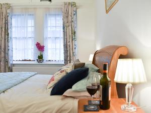 a bed with a bottle of wine and two glasses on a table at Ukc4174 The Cottage By The Sea in Littlehampton