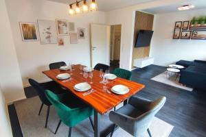 a dining room with a wooden table and green chairs at Ferienhaus an der Elbe - XR32 in Seevetal