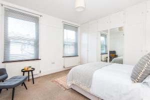 1 dormitorio con 1 cama, 1 silla y ventanas en King Room with a shared Kitchen and bathroom in a 5-Bedroom House at Hanwell, en Hanwell