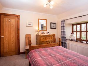 a bedroom with a bed and a dresser and a mirror at Craigellachie Cottage in Croy