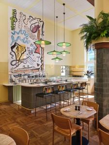 a restaurant with tables and chairs and a large mural at The Hoxton, Lloyd Amsterdam in Amsterdam